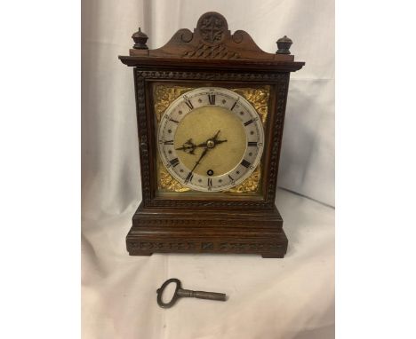 A DECORATIVE OAK CASED MANTLE CLOCK WITH GILT FACE AND ROMAN NUMERALS AND A KEY 