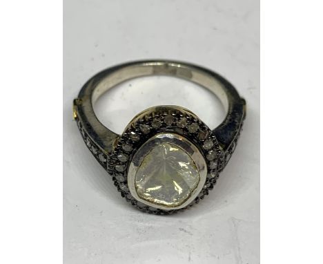 A CONTINENTAL WHITE AND YELLOW METAL RING WITH CENTRE DIAMOND AND SMALLER SURROUNDING DIAMONDS WHICH CONTINUE ON THE SHOULDER