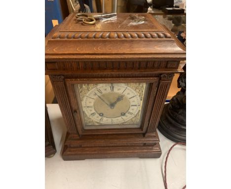 AN OAK CASED CHIMING MANTLE CLOCK WITH DECORATIVE GILT FACE WITH ROMAN NUMERALS COMPLETE WITH BOTH KEYS 