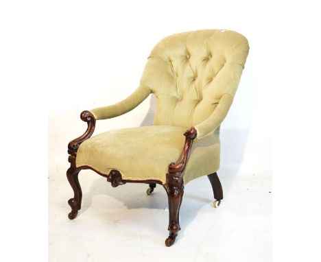 Victorian carved walnut framed spoon back deep buttoned easy chair with open arms on scroll supports and French cabriole fron