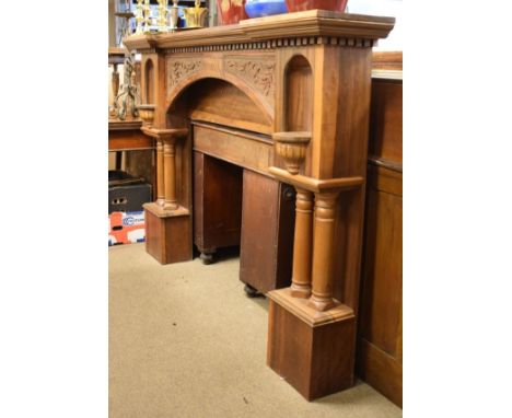 Impressive early 20th century carved walnut fire surround of inverted breakfront design with stipple-carved arch between nich
