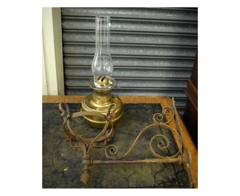 Wrought iron wall mounting lamp bracket with brass bodied paraffin lamp beneath glass chimney   Condition: 