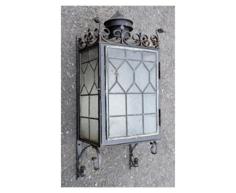 Early 20th Century wrought iron wall lantern, with mottled glass door and sides all with lead tracery with scroll cresting an