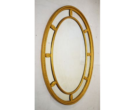 Early 20th Century giltwood oval wall mirror having central oval plate within partitioned surround and gadrooned frame   Cond