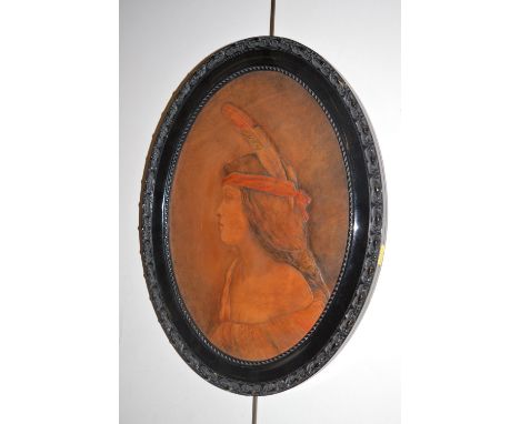 An oval leather panel depicting female portrait of a girl with long hair wearing a feather and a band, in ebonised moulded fr