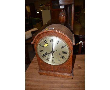 A large inlaid oak mantel clock with arched case and silver-coloured roman dial.