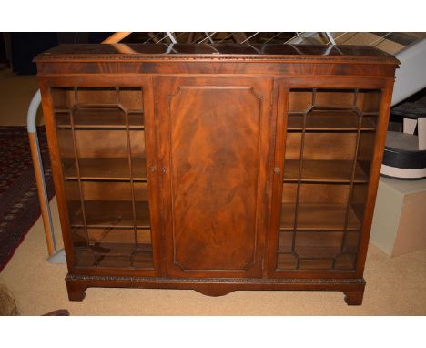 A mid 20th Century mahogany bookcase, with solid central panel door flanked by two glazed panelled doors enclosing shelves, r