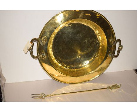 A Middle Eastern brass two-handled circular dish; together with a brass toasting fork. (2)
