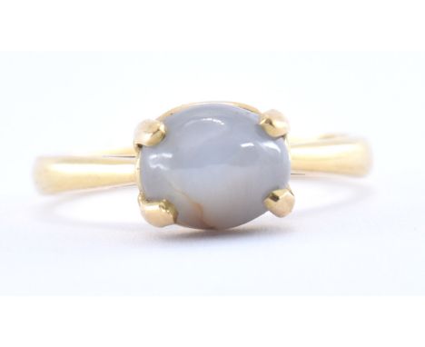 A hallmarked 18ct gold star sapphire ring. the ring set with a bluish grey oval star sapphire ( approx 8mm x 4mm) cabochon in