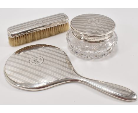 A 1930's Mappin &amp; Webb silver backed dressing table set. The set to include a clothes brush, lidded jar and hand mirror a
