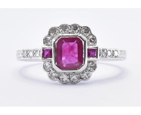 An 18ct white gold ruby and diamond ring set with a central emerald cut ruby flanked by two further square cut rubies and wit