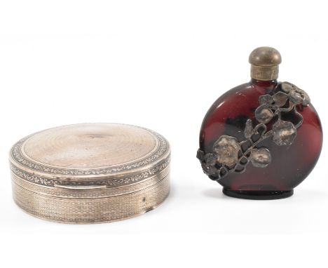 An early 20th Century silver hallmarked dressing table box of round form having engine turned decoration with moulded floral 