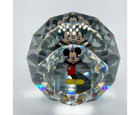 Faceted crystal globe decorated with a smiling Mickey with arms wide in greeting. Colored in black, white and red with yellow