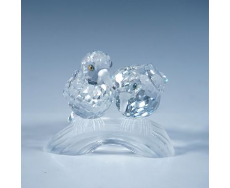 A clear faceted sculpture of two loving birds with iridescent eyes and frosted beaks and feet, perched on a frosted branch. 1