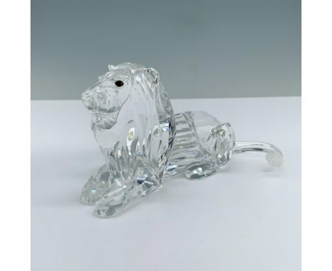 A lion lying down peacefully on all fours, with striking amber crystal eyes. Swarovski backstamp. This item has its original 