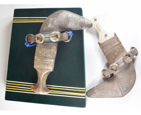 Two presentation Jambiya daggers, both with ornate white metal decoration to the scabbards, one with rhino style horn handle 
