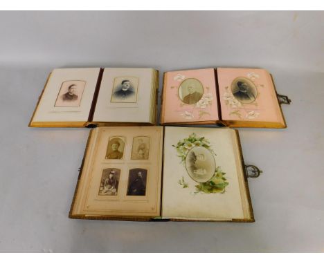 Three Victorian tooled leather photograph albums, two clasped, with decorated pages, some portrait photographs.