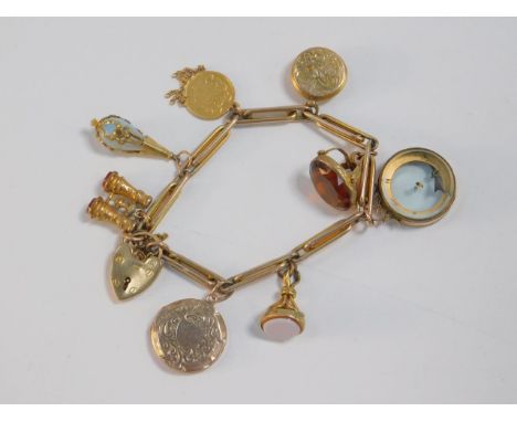 A 9ct gold cable link charm bracelet, set with nine charms, as fitted, including three fobs, a compass and a US Liberty head 