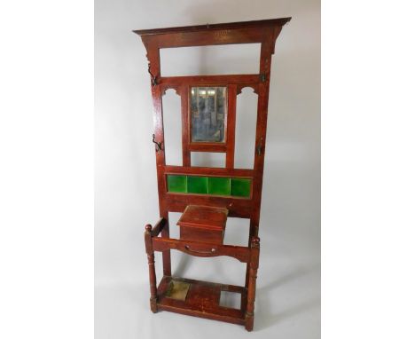 A Victorian stained oak hall stand, the back inset with a bevelled glass mirror, above a four green tile splash back, with a 