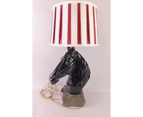 A black plaster table lamp modelled as a horse's head, on a square base, with a pleated white and red fabric shade, 67cm high