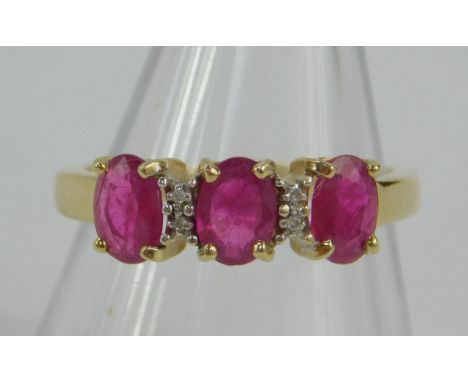 A 9ct gold and ruby three stone ring, set with pairs of diamonds at intervals, size M,  2.6g.