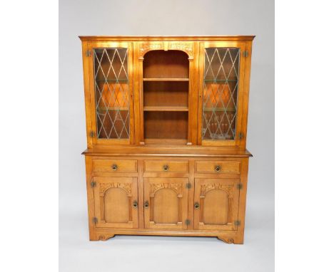 An oak dresser, the top with a centre open section of two shelves, flanked by two astragal glazed doors each enclosing two gl