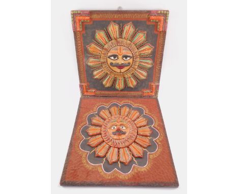 A pair of 20thC Mayan plaster Sun God wall plaques, of facial form, brightly painted in relief, each 46cm x 46cm.