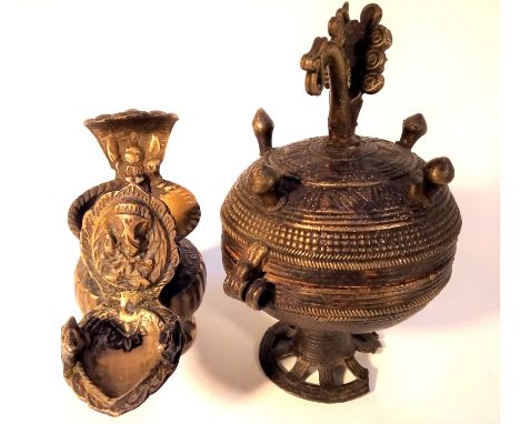 Cast brass container and lamp from India. The pot is used for kohl or binde, the lamp is a small oil lamp with an image of Ga