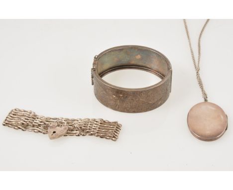 A silver 25mm wide half hinged bangle, engraved pattern to front, hallmarked Chester 1952, a silver oval locket with floral e