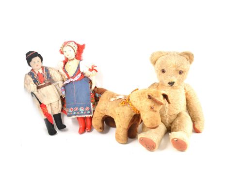 A vintage 1950s straw filled teddy bear, 49cm tall, a straw filled dog, and two character dolls.