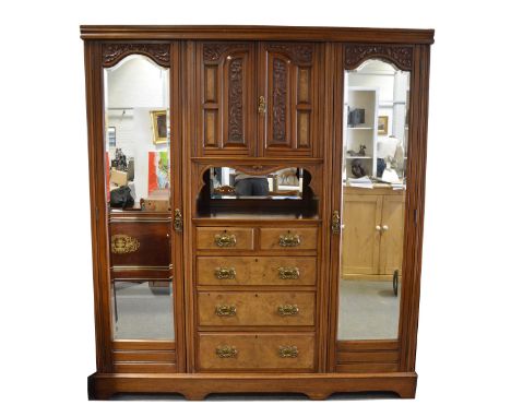 A late Victorian walnut triple wardrobe, moulded cornice, fitted with carved panelled doors, two short and three long graduat