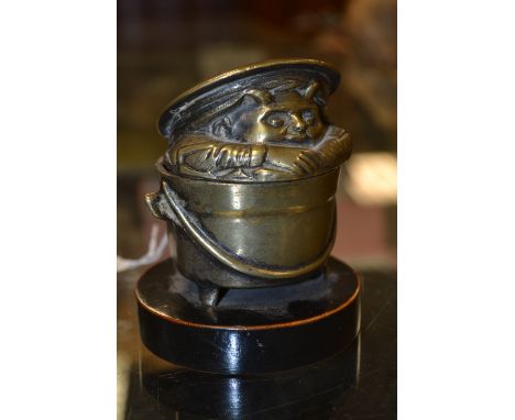 A 19th century bronze comical novelty inkwell, cast as devilish boy peering out of a cauldron, hinged cover, circular ebonise