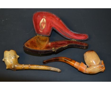 A French clay pipe, fashioned as a hand holding the bowl of the pipe, resin mouth piece, cased; another similar, modelled nat