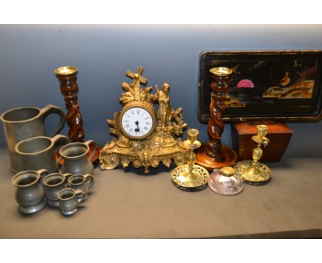 A gilt metal mantel clock, decorated with harvest motifs; a pair of barley twist oak candlesticks; pewter measures; pewter mu