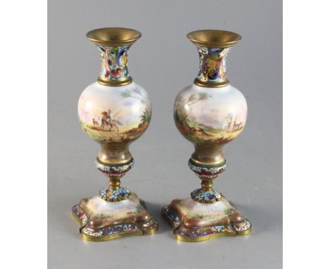A pair of early 20th century French champleve enamel and porcelain candlesticks decorated with arabs in landscapes 7.5in.http