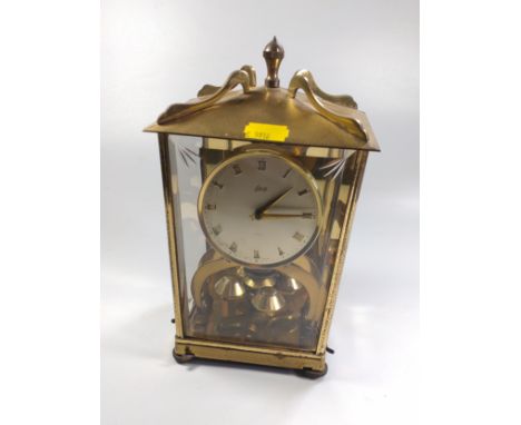 A brass mantel /lantern clock, glass panelled, with rotating ball pendulum, the silvered dial with Arabic numerals. 