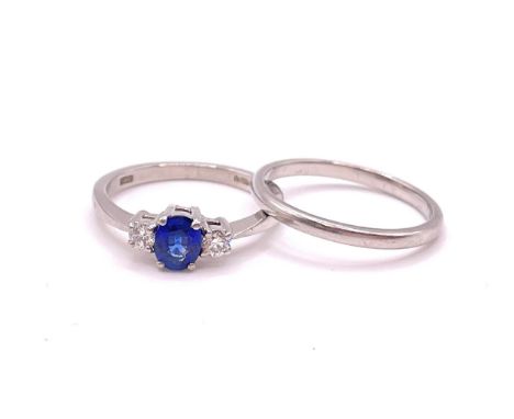 A platinum, diamond, and sapphire ring, set with a mixed oval-cut sapphire, flanked with two round brilliant-cut diamonds of 