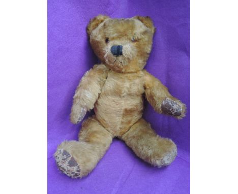 A mid 20th century straw filled yellow plush teddy bear having plastic eyes, stitched nose and mouth and jointed body