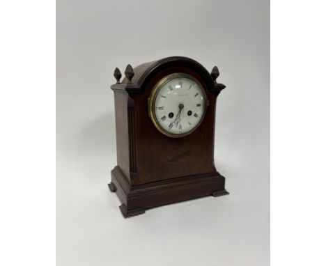 An Edwardian mahogany mantle clock with enamelled dial and chequered boxwood and ebony inlay, raised on four brass bracket fe