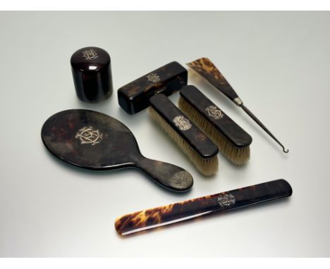 An Edwardian seven-piece tortoise shell ladys set mounted with cypher C. H in silver gilt to include and hand mirror: l. x 26