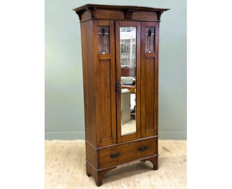 An Edwardian oak Glasgow school style arts and crafts wardrobe with moulded top and centre mirror door, flagged by stained gl