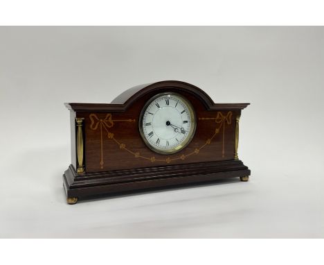 An Edwardian mahogany mantel clock with satinwood inlaid decoration in the shape of bows and flowers, with brass mounts and p