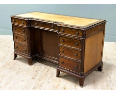 An Edwardian mahogany twin pedestal knee hole writing desk with shaped top and inset leather sciver above a centre frieze dra