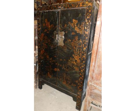 A 19thC Chinese black lacquer cupboard, decorated overall with buildings, trees, rocks, etc., in gilt, with two panelled door