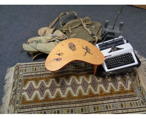 A shaped stool together with a cased Erika typewriter and a box containing two vintage rucksacks, fire companion set, Persian