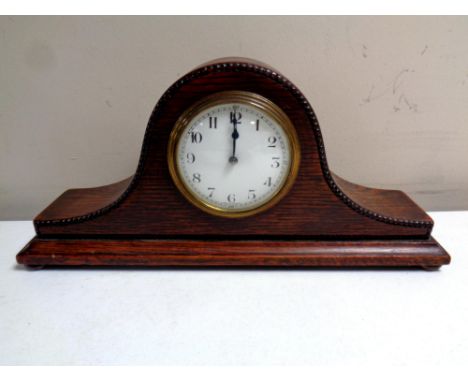 An Edwardian oak cased mantel clock on bun feet 