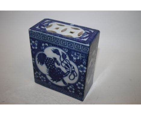 A CHINESE BLUE AND WHITE CERAMIC OPIUM PILLOW, with foo dogs to all sides amongst foliate detail, H 13.5 cm