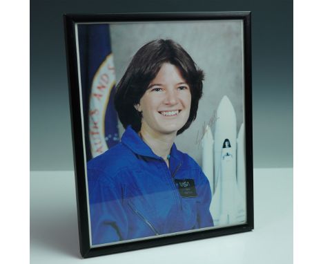 Color portrait photograph of astronaut Sally Ride, signed in marker on the right side of the image. Depicting Ride in her NAS