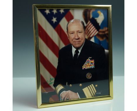 Color photograph portrait of Admiral William J. Crowe Jr., shown in full dress uniform against a patriotic backdrop featuring