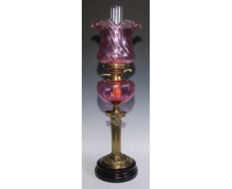 A Victorian brass Corinthian column oil lamp, cranberry glass shaped and reservoir, 62cm high, c.1900